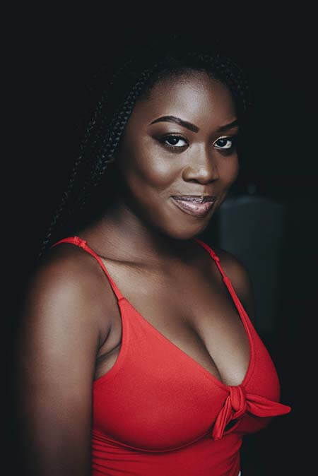 Black womxn with a professional long dreadlocks hairstyle wearing a red top smiling to the camera