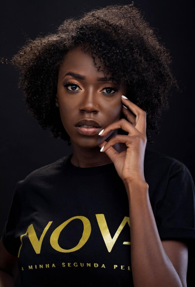Black womxn with professional workplace makeup, copper eyeshadow, black eyeliner and mascara, looking to the camera