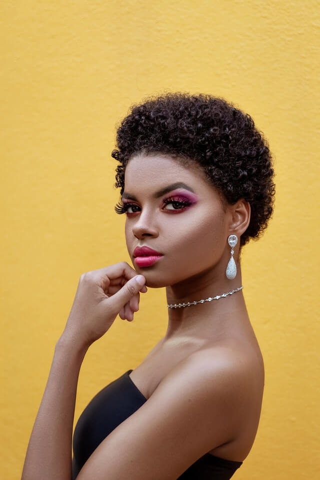 Black womxn with professional short afro, workplace makeup, pink lipstick and eyeshadow, looking to the camera
