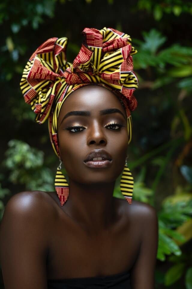 Black womxn with turban, workplace makeup, wearing rose lipstick and eyeshadow, looking to the camera