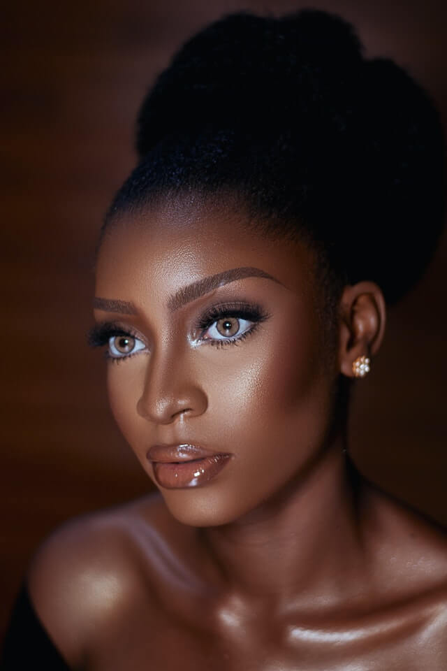 Black womxn with workplace makeup, lipgloss and cat eye lashes, looking to the side